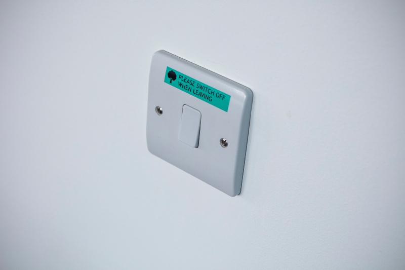 White light switch on wall with a green label on it