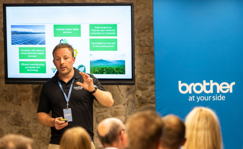 Man presenting to an audience of people with a screen in the background