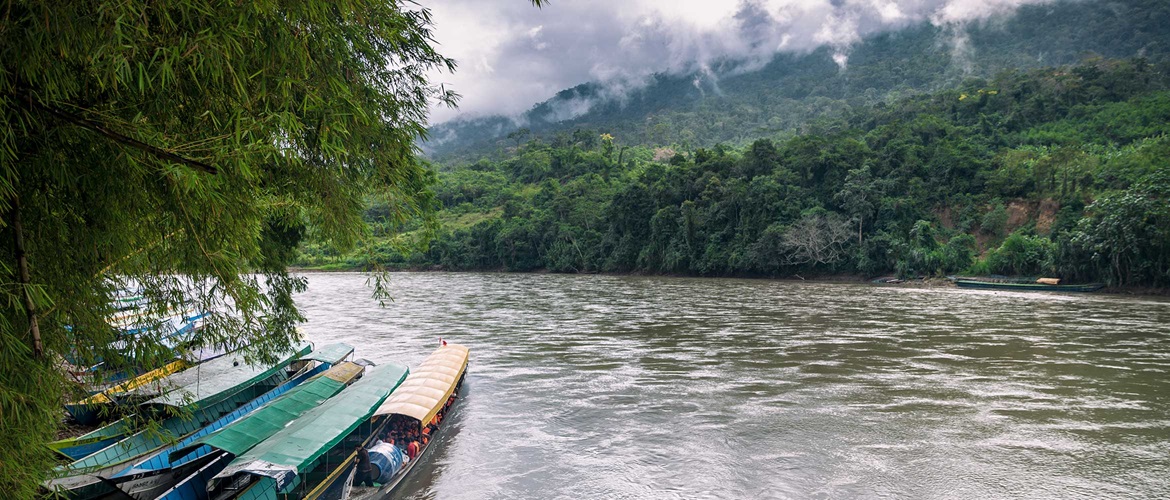 River in between mountains with boats on the side
