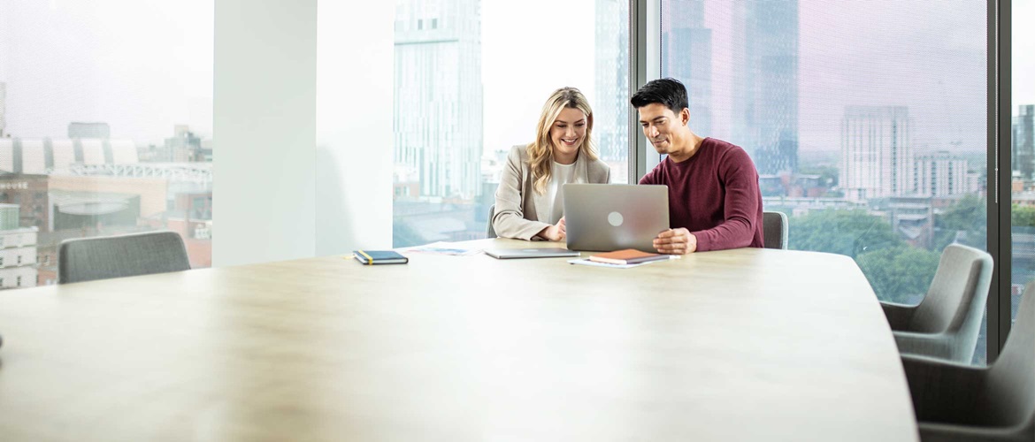 Man and a woman sat at a desk on a laptop
