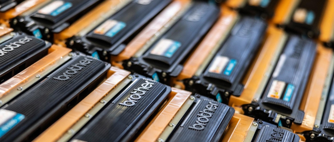 3 rows of orange and black Brother toner cartridges lay side by side