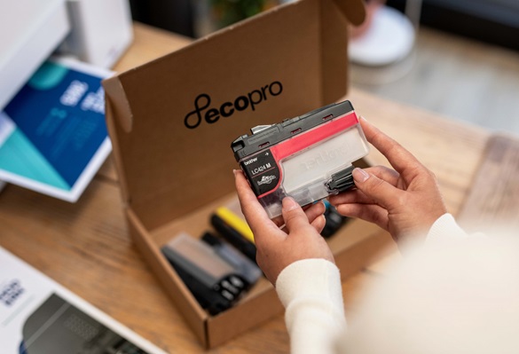 Woman holding an ink cartridge with an open box on the table next to a printer