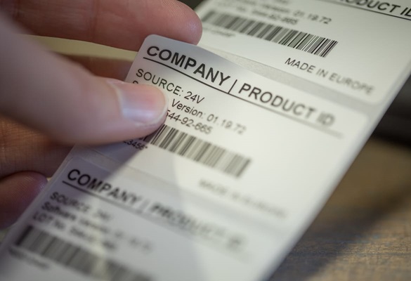 Närbild på en person som applicerar en etikett från Brother med Produktinformation på