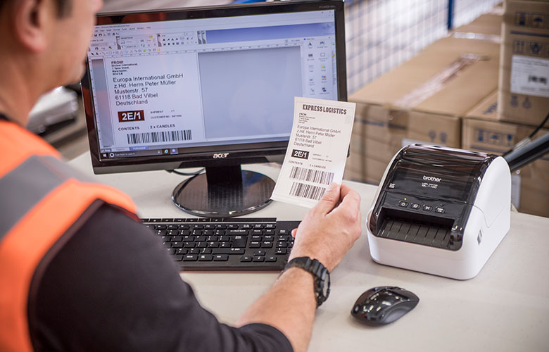 Brother QL printer next to monitor with shipping label printed in warehouse