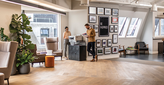 Man and woman standing by Brother printer, looking at printouts